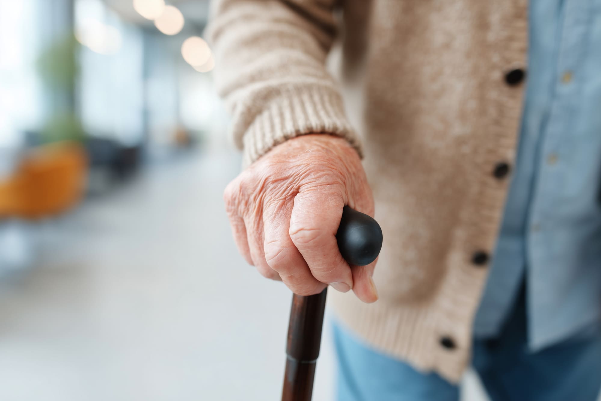 Gros plan sur la main d’une personne âgée s’appuyant sur une canne pour se déplacer.