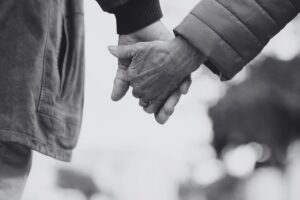 Gros plan sur les mains d’un couple âgé se tenant la main, symbolisant le soutien et le lien affectif.