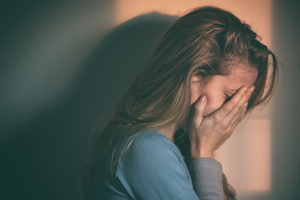 Jeune femme, le visage dans les mains, exprimant un sentiment de culpabilité et de détresse émotionnelle.